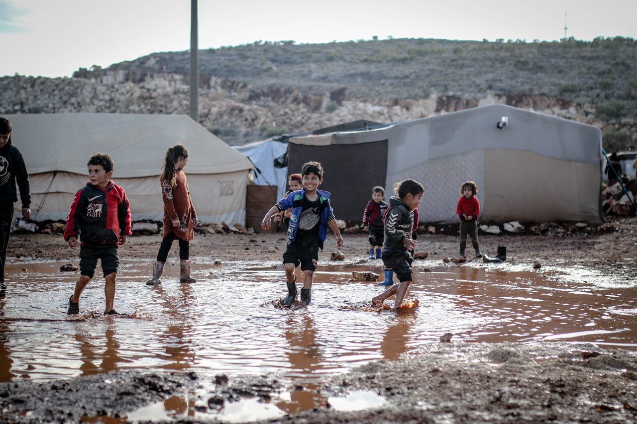 Kids enjoying playtime in a muddy refugee camp in Idlib, Syria amidst challenging conditions.