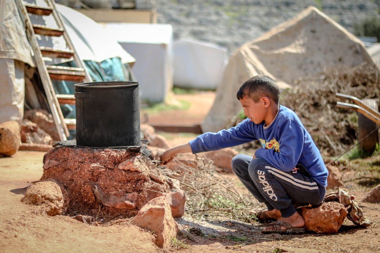 about-us A young boy tends to a cooking pot outdoors in a refugee camp in Idlib, Syria.